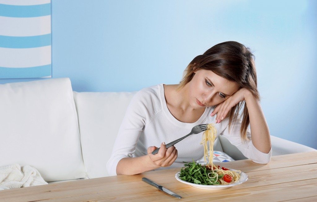 sad girl trying to eat pasta