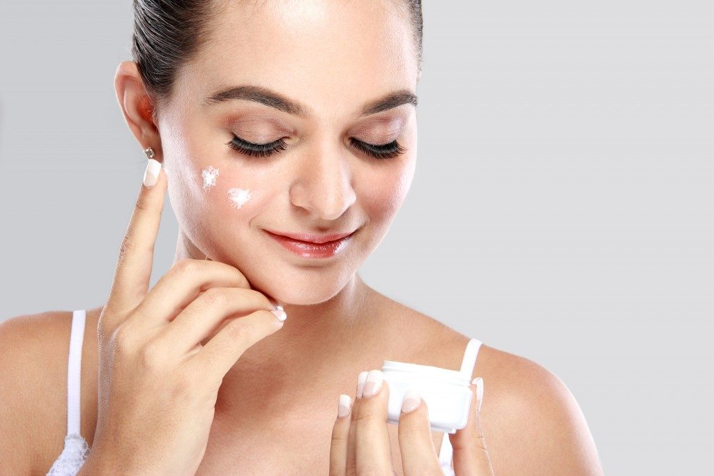 Woman applying cream skin care