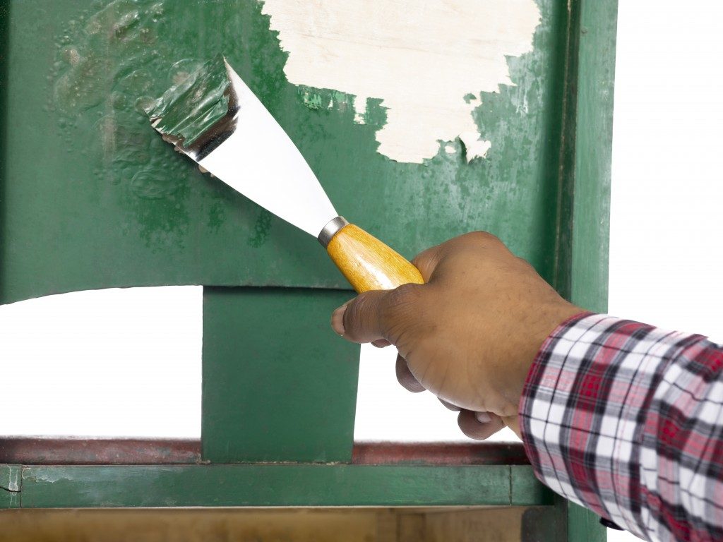 man scraping paint off the wall