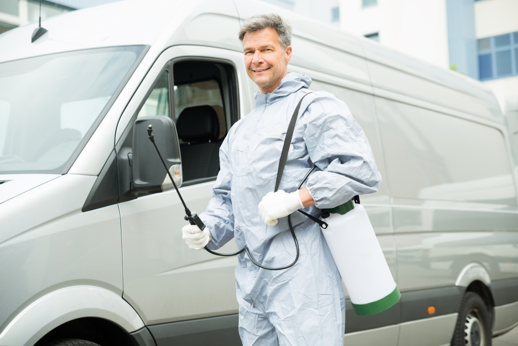 Happy Worker With Pesticide Sprayer Standing In Front Van