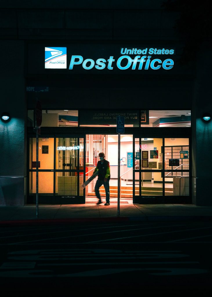 man standing in us post office doorway at night