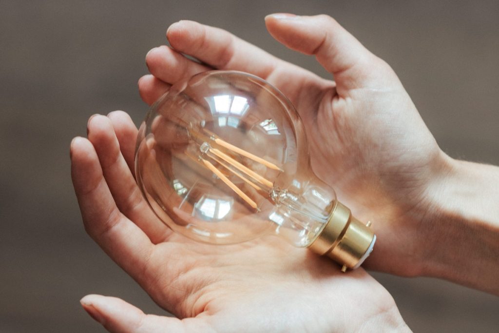 Unrecognizable woman demonstrating light bulb in hands