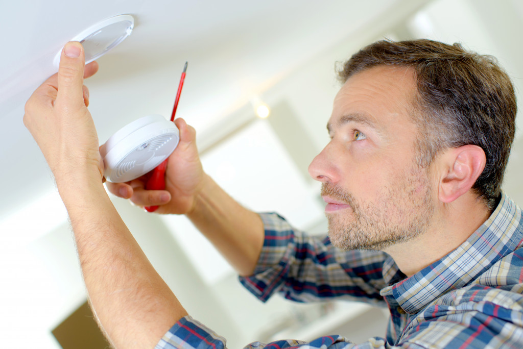 A man installing a smoke alarm on the ceiling