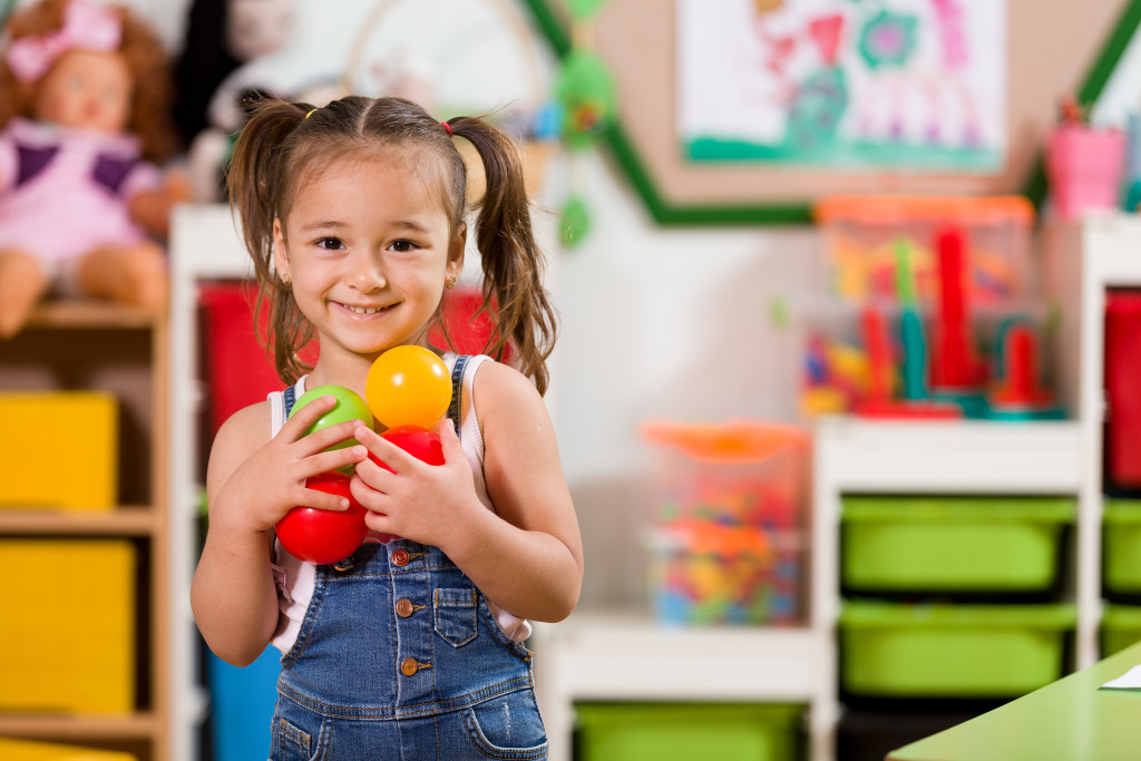 little girl holding balls toy storage background