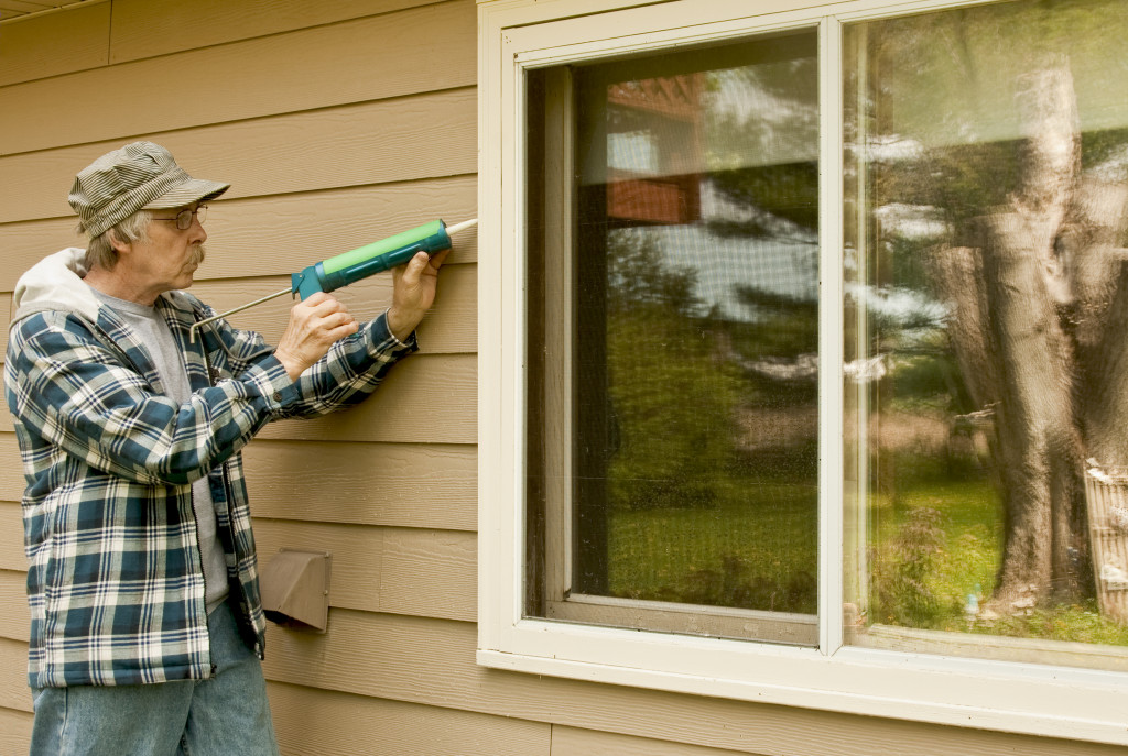 a senior man sealing a window