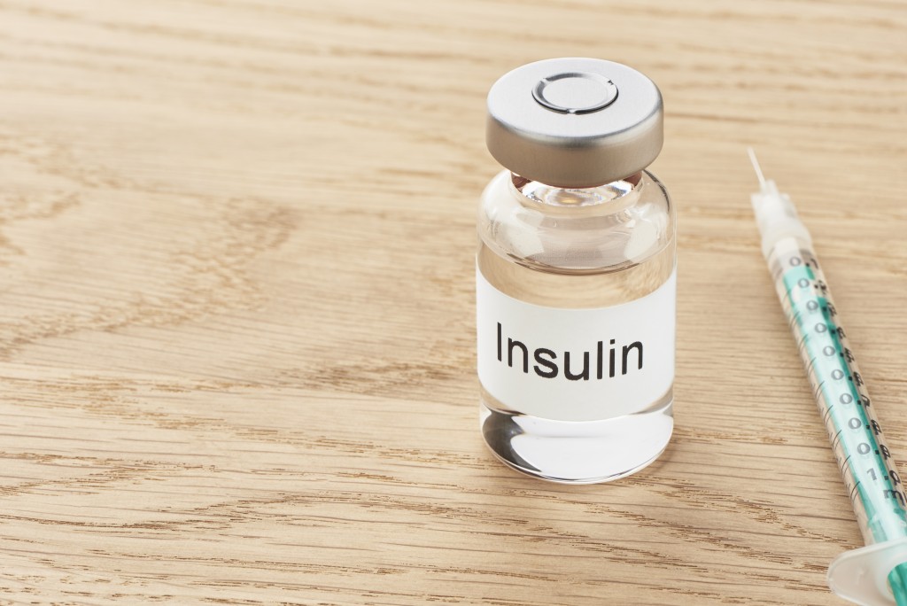 insulin ampoule and syringe on wooden table