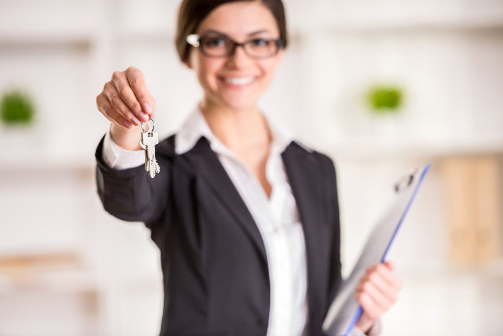 landlord with glasses smiling while handing over a key