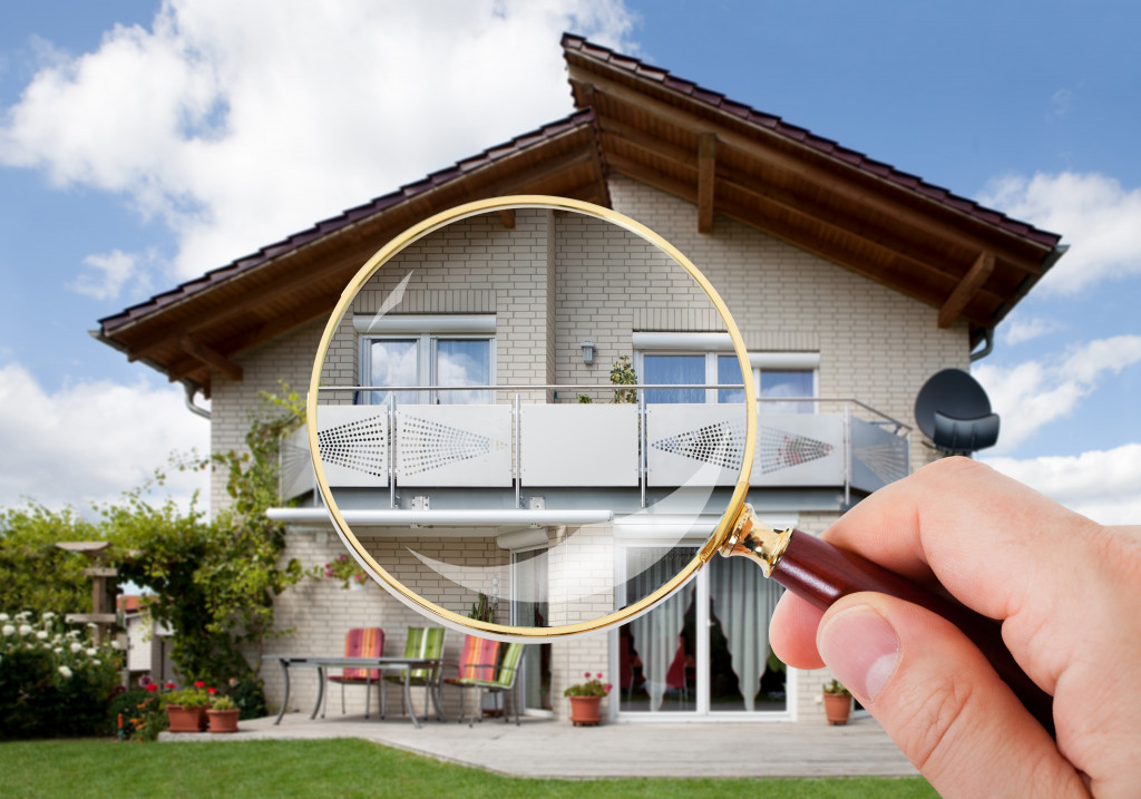 property maintenance represented by a hand holding a magnifying glass over a house