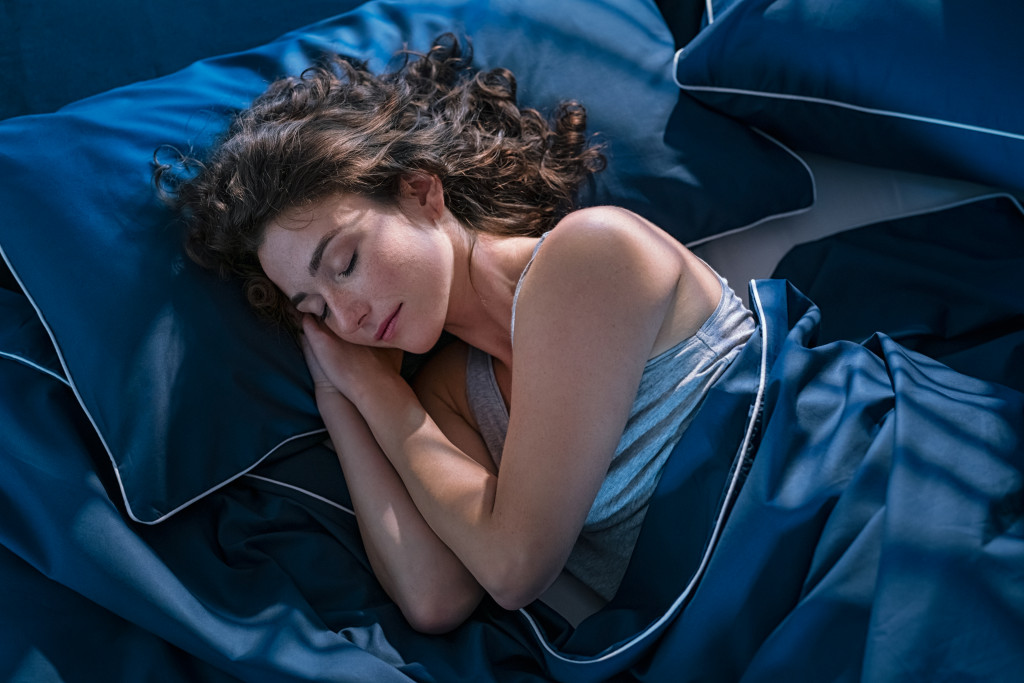 woman asleep in blue silk sheets