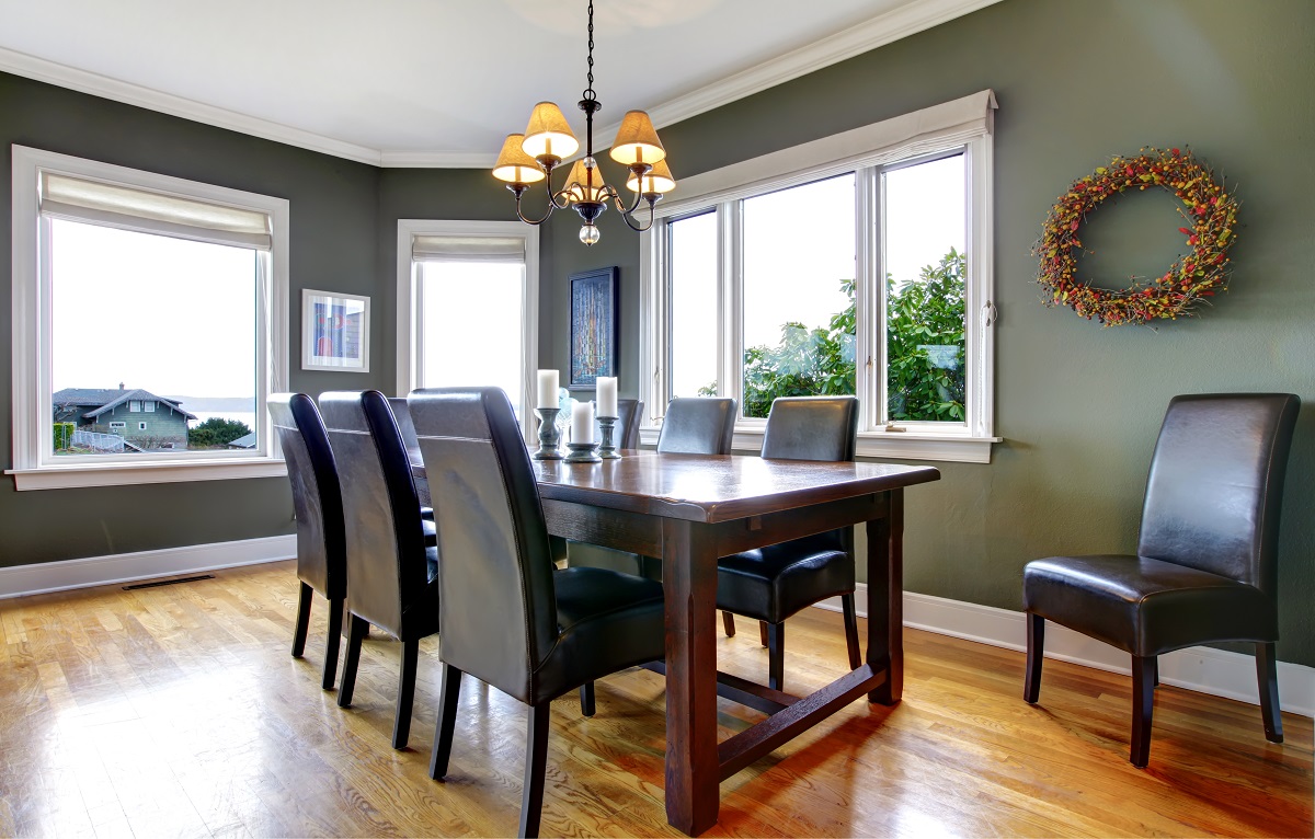 Large dining table with leather chairs in a dining area with large windows.